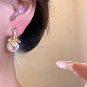 Eleganti orecchini a pendente con zirconi e perle placcati in oro 18 carati su orecchio