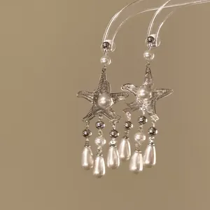 Detailed view of silver starfish dangle earrings featuring elegant pearl tassels and drop charms.