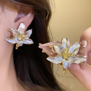 Macro detail of retro lily flower earrings with white enamel finish and golden edges