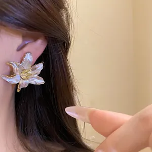 Elegant vintage white oil drip flower stud earrings shown on an Asian model's ear.