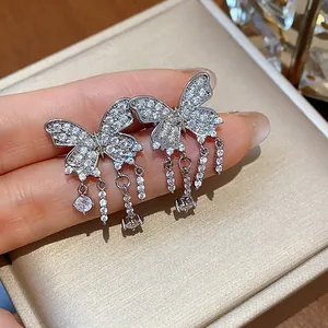 Macro view of butterfly tassel ear clips encrusted with sparkling cubic zirconia.