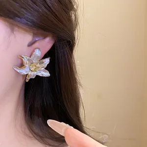 Close-up of vintage white enamel lily flower stud earrings on model's ear