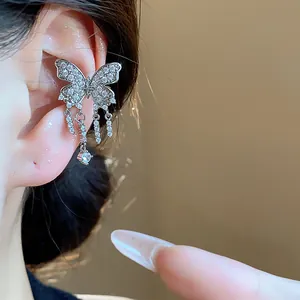 Detailed macro view of a sparkling silver zircon butterfly ear cuff with tassels worn on ear