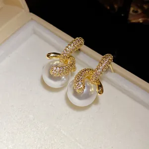 Dettaglio macro degli orecchini di perle placcati oro 18K con zirconi brillanti.