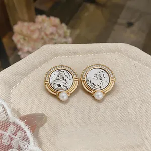 Macro view of luxury vintage round stud earrings with horse head motif and white pearl