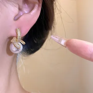 Primo piano di eleganti orecchini pendenti con perle e zirconi placcati in oro 18K