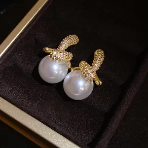 Primo piano di eleganti orecchini di perle placcati oro 18K con zirconi