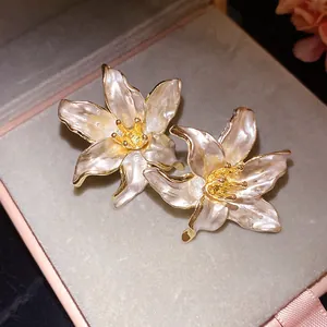 Close-up of vintage pearlescent white drip oil flower earrings with gold edges