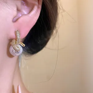 Primo piano dettagliato di un orecchino pendente in oro 18k con zirconi e perla