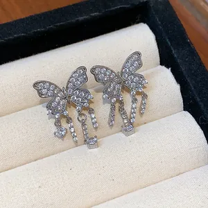 Close-up detail of elegant silver-colored butterfly earrings with sparkling zirconia tassels