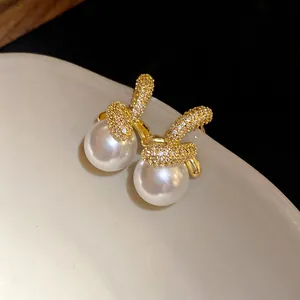 Primo piano di eleganti orecchini a perno con perle e zirconi placcati in oro 18 carati