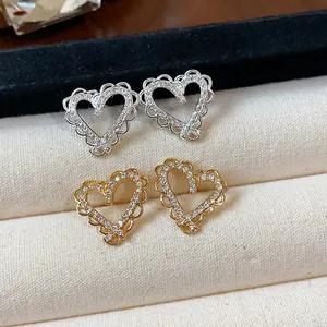 Detail view of heart-shaped stud earrings with gold and silver plating and zircons.