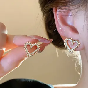 Close-up of gold-plated heart-shaped earrings with sparkling zircon stones on a model.