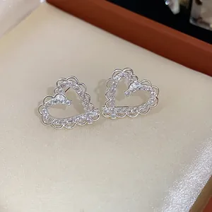 Close-up of exquisite heart stud earrings with sparkling zirconia and silver needles.