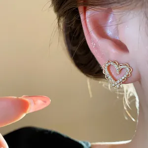 Detail view of elegant heart-shaped zircon earrings with 18k gold plating on the ear
