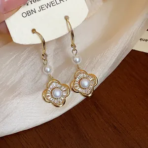 Gros plan détaillé de boucles d'oreilles vintage en or avec fleurs, perles et zircons sur carte.