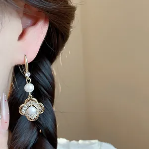 Vue détaillée de boucles d'oreilles fleur évidée avec perle et zircon portées à l'oreille