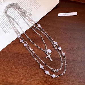 Elegant multi-layered pearl necklace with rhinestone cross pendant on wooden background