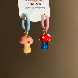 Dettaglio di orecchini a cerchio asimmetrici a forma di fungo con vetro colorato
