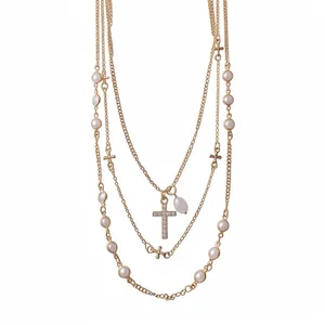 Multi-layered gold necklace featuring white faux pearls and a sparkling rhinestone cross.