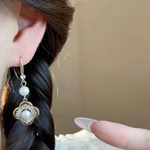 Gros plan de boucles d'oreilles fleur vintage en or avec perles et zircons brillants.