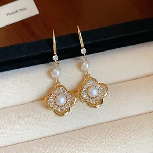 Gros plan exquis de boucles d'oreilles fleur dorées avec perles et zircons en boîte