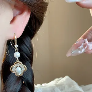 Gros plan sur une boucle d'oreille trèfle dorée avec perles et zircons étincelants