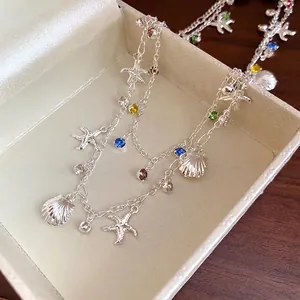 Collier double argenté avec breloques étoile de mer et coquillage et strass colorés chic.