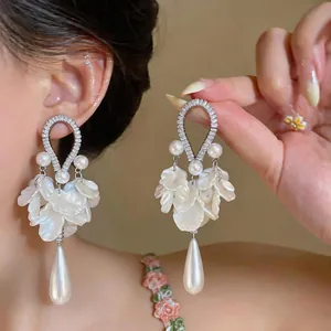Dettaglio di orecchini vintage francesi con zirconi, perle e pendenti a petalo bianchi