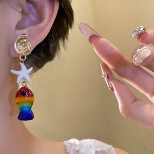 Vista dettagliata dell'orecchino a forma di conchiglia e pesce arcobaleno sull'orecchio