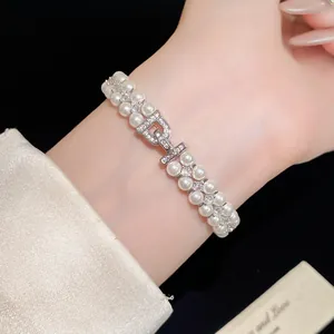 Close-up of double-layer pearl bracelet with zircon encrusted D-shaped clasp on wrist.
