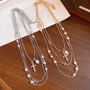 Close-up of elegant layered cross and pearl necklaces on a vintage paper background