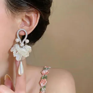 Dettaglio di orecchini retrò in zircone con perle eleganti e petali bianchi delicati