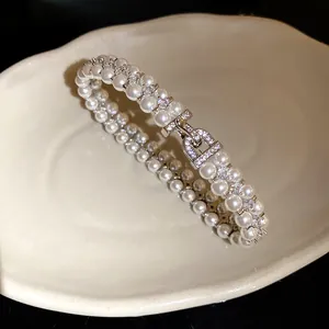 Detail view of double-layer pearl bracelet with zircon-encrusted buckle.