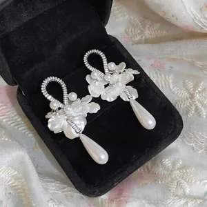 Dettaglio di eleganti orecchini vintage con perle, petali di zircone e pendenti a goccia