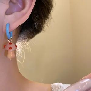 Primo piano di un orecchino a forma di fungo rosa indossato sull'orecchio di un modello
