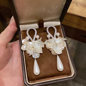Dettaglio di eleganti orecchini vintage con zirconi e petali di perla in una scatola
