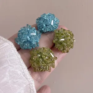 Gros plan sur d'élégantes boucles d'oreilles boules de cristal bleu et vert lime.