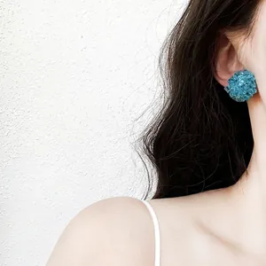 Vue détaillée d'élégantes boucles d'oreilles en sphère de perles bleues au design texturé.