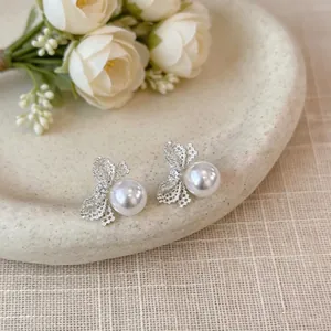 Dettaglio ravvicinato di eleganti orecchini a fiocco d'argento con perla bianca