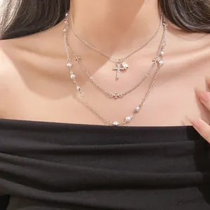 Close-up of a three-layer silver necklace with diamond cross and pearls on a model