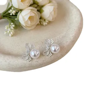 Eleganti orecchini a lobo a fiocco in argento con perle su un piatto bianco