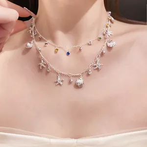 Détail d'un collier argenté à deux rangs avec étoiles de mer, coquillages et strass colorés.