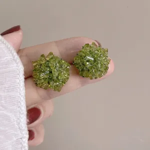 Vue macro de boucles d'oreilles boules de fleurs vertes avec cristaux facettés brillants