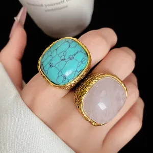 Close-up view showing vintage square rings with turquoise and rose quartz stones on hand