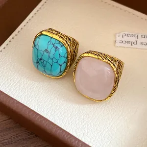 Detailed view of vintage square turquoise and rose quartz rings with textured gold bands