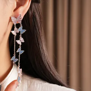 Dettaglio dei lunghi orecchini a nappa con delicate farfalle in zircone rosa e blu.