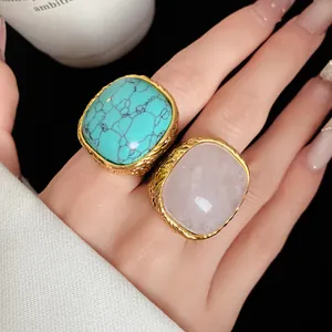 Close-up view of vintage gold rings featuring square turquoise and pink quartz stones