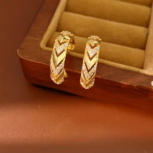 Close-up detail of 14k gold plated C-shaped hoop earrings with V-pattern zircons.