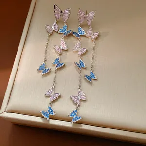 Dettaglio degli orecchini a farfalla con zirconi rosa e blu su base argentata.